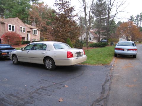 1991 Ford LTD Crown Victoria - A beige sedan is parked in a driveway next to another car, with a house in the background.