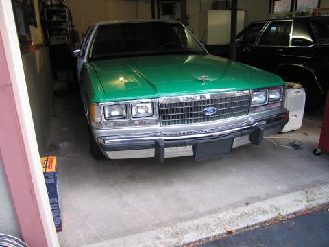 1991 Ford LTD Crown Victoria - A green Ford Crown Victoria is parked in a garage, with another vehicle visible behind it.