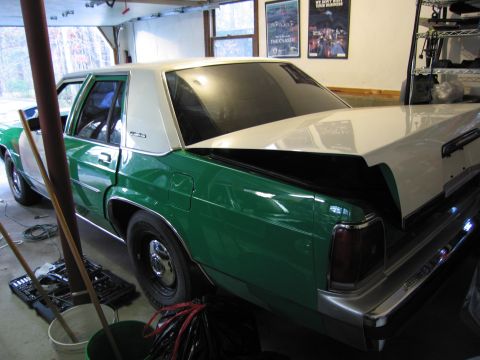 1991 Ford LTD Crown Victoria - A two-tone green and white 1991 Ford Crown Victoria LTD is parked in a garage with its trunk open.