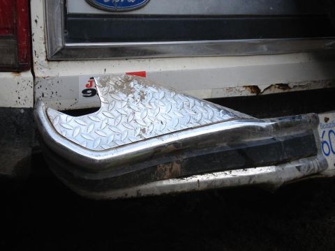 1986 Ford Bronco - Close-up of a vehicle's rear bumper, showing a diamond plate cover and signs of rust.