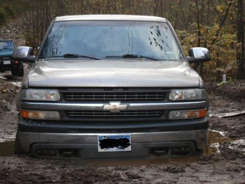 1986 Ford Bronco - Chevrolet Silverado stuck in mud off-road, another vehicle is visible in the background.