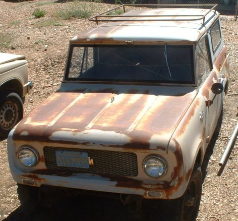 1961 International Scout 800 - Front view of a heavily rusted 1961 International Scout 800 with a roof rack. Another vehicle is partially visible on the left.