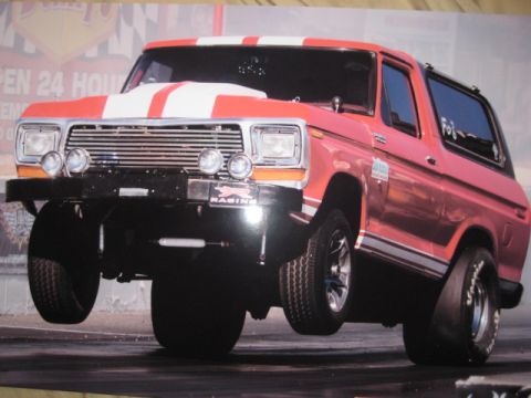 1979 Ford Bronco - A red and white striped 1978 Ford Bronco is captured mid-air during a drag race event.