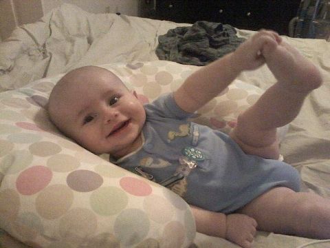 1997 Ford F-250 - A smiling baby is captured in a playful pose on a bed, reaching for its foot.