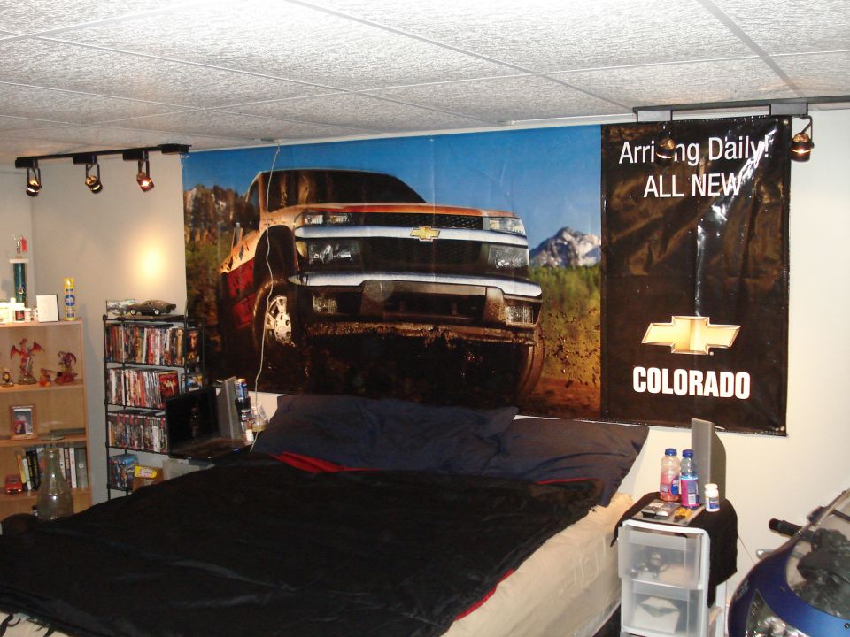 Chevrolet Colorado dealership banner of a muddy red pickup hung on a bedroom wall