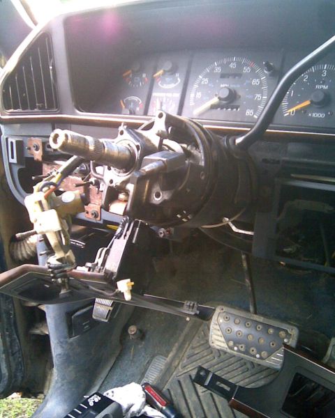 1989 Ford Bronco - Interior view of a truck dash with the steering wheel removed and the steering column dropped and partially disassembled, exposing the spli…