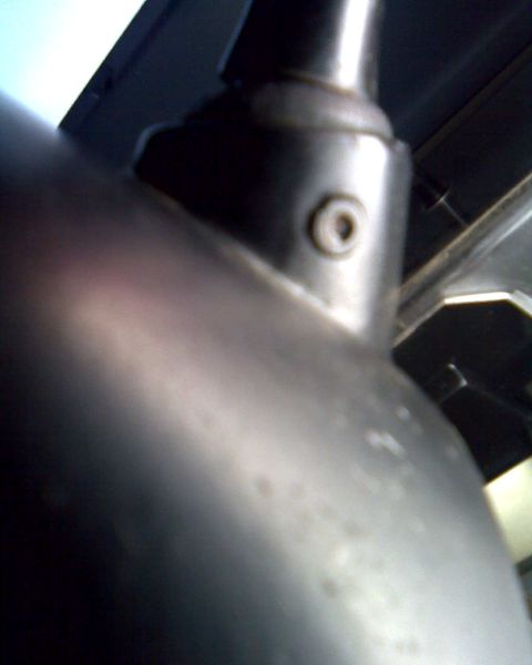 1989 Ford Bronco - Blurry close-up shot from beneath the dash looking up along a bare metal steering column tube, showing the welded seam, a threaded shroud-s…