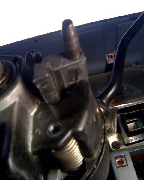 1989 Ford Bronco - Extreme close-up inside a truck cab of an exposed steering column with its shrouds off, showing the cast tilt housing, coil spring, brass s…