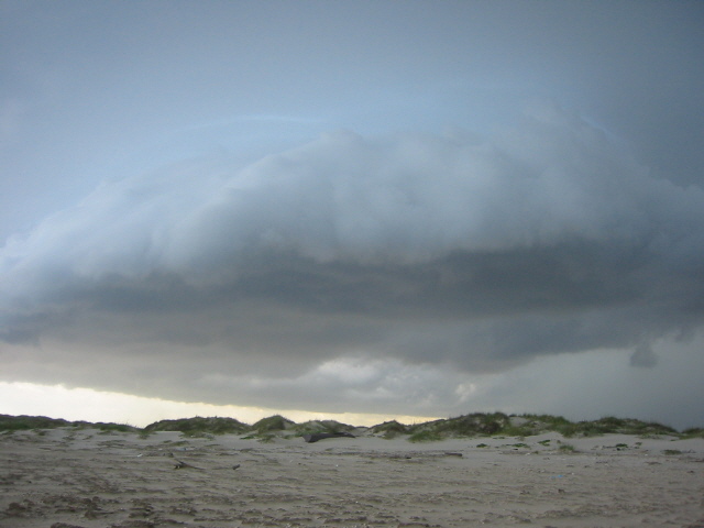 Storm clouds gather over sand dunes and beach