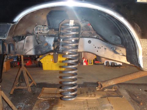 1996 Ford Bronco - This image shows a vehicle's suspension system, focusing on a large coil spring and surrounding frame components.
