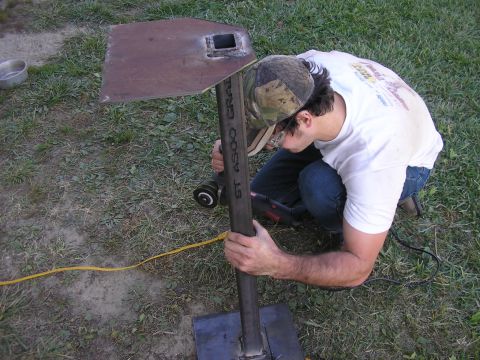 1996 Ford Bronco - Man uses a grinder on a metal post with visible text, outdoors.