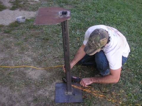 1996 Ford Bronco - A person is using an angle grinder to cut a metal post on a stand outdoors.