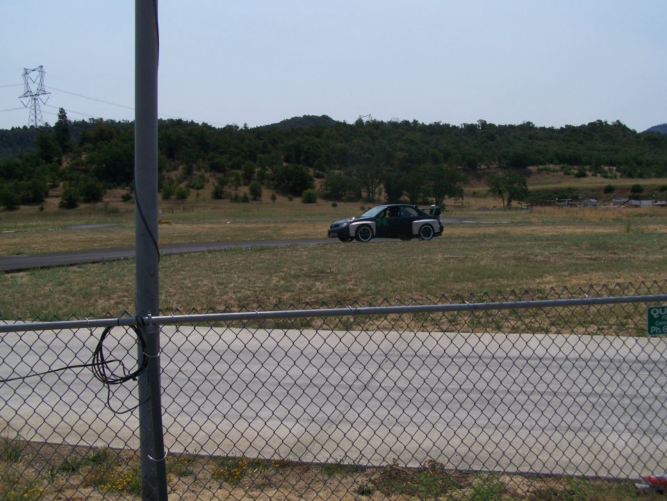 Modified car with large rear spoiler on a grassy field
