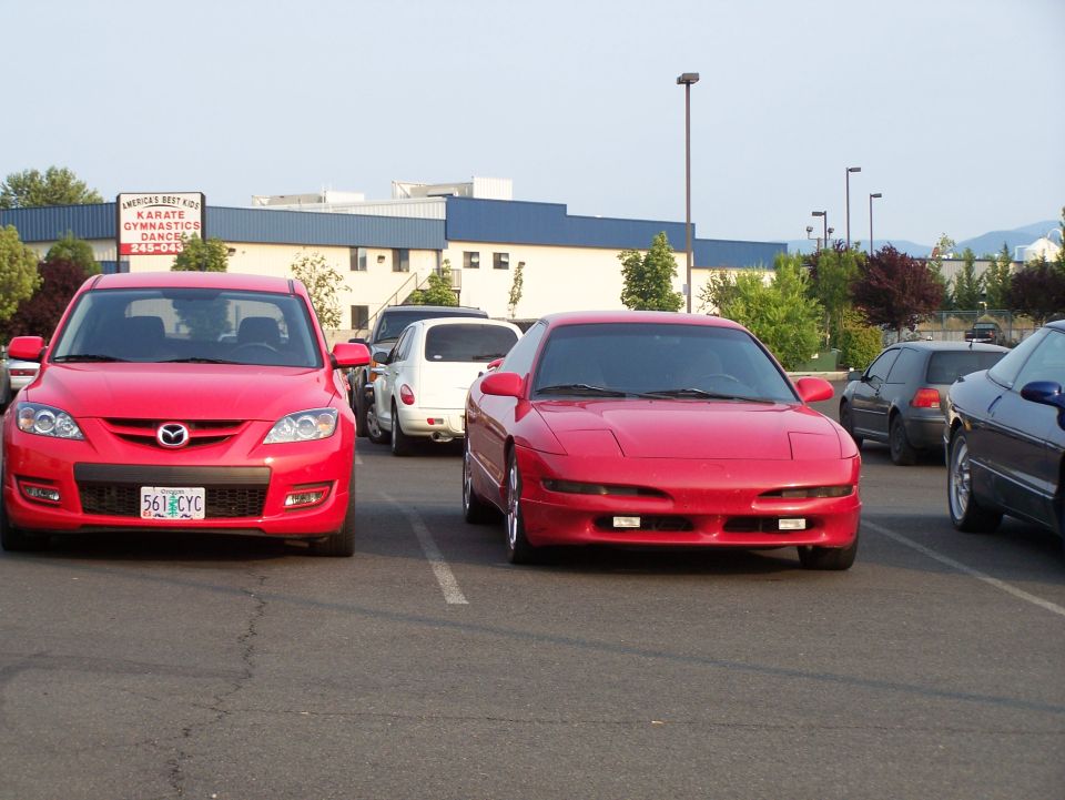 Red 2007 Mazda 3 parked in a lot, with other cars in the background.