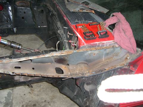 1988 Ford Bronco - A car's frame is being worked on, with tools and a rag placed on the red metal section.