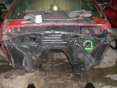 1988 Ford Bronco - The engine bay of a red vehicle is shown, with the frame and wiring exposed, indicating it is undergoing work.