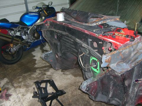 1988 Ford Bronco - A disassembled vehicle front end sits next to a blue motorcycle in a garage.