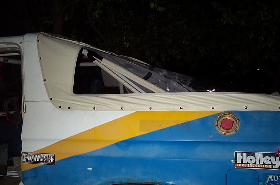 White, blue and yellow Bronco side view at night with tan soft top and Flowmaster and Holley stickers