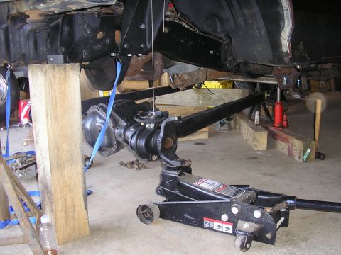 1996 Ford Bronco - Vehicle undercarriage and suspension components are being worked on, supported by blocks and a jack.