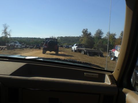 1989 Ford Bronco - Several vehicles are parked in a field on a clear day, with trees in the background.