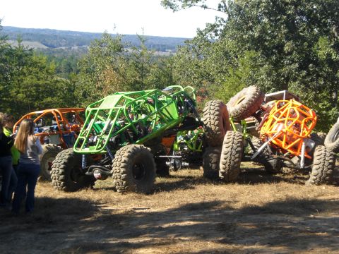 1989 Ford Bronco - Multiple custom off-road vehicles are gathered outdoors on a sunny day.