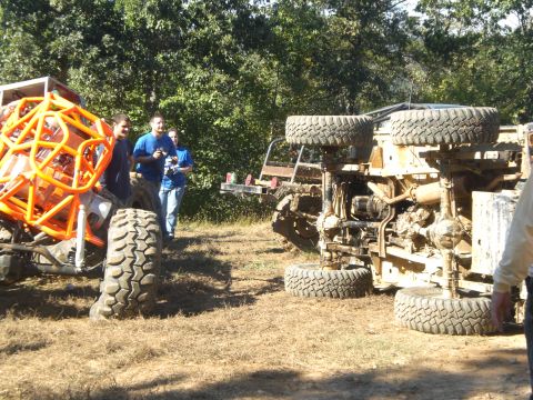 1989 Ford Bronco - An off-road vehicle has overturned, with another vehicle and people nearby.