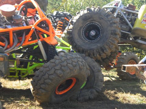 1989 Ford Bronco - Several heavily modified off-road vehicles are parked together in a grassy area.