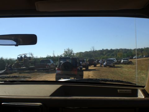 1989 Ford Bronco - A group of off-road vehicles are parked on a dirt road under a clear blue sky.