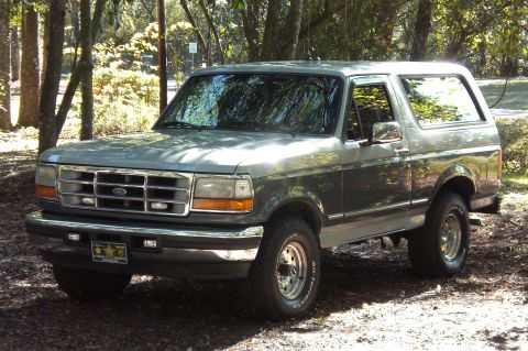 1996 Ford Bronco - This 1996 Ford Bronco is parked on a dirt path surrounded by trees.