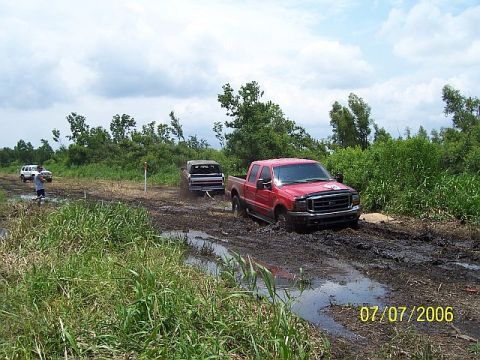 1979 Ford Bronco - Multiple vehicles navigating a muddy off-road course on a cloudy day.