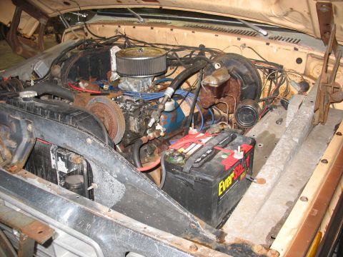 1978 Ford F-250 - The engine bay of a 1978 Ford F-250 shows its V8 engine, battery, and radiator, with visible signs of wear.