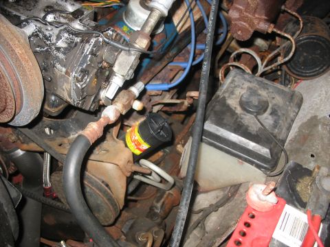 1978 Ford F-250 - Close-up view of a cluttered and aged engine bay, showing various mechanical components and fluid reservoirs.