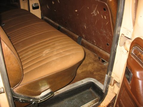 1978 Ford F-250 - The interior of a truck shows a worn brown bench seat and the lower section of the door panel.