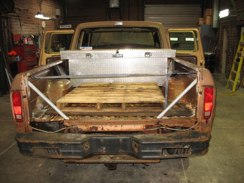 1978 Ford F-250 pickup truck rear view showing bed with toolbox and pallet, rust on bumper and bed