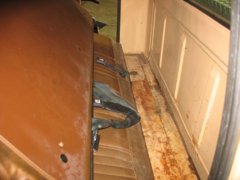 1978 Ford F-250 - The interior of a truck shows a brown bench seat and a worn, rusty wooden floor.