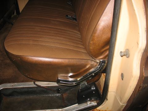 1978 Ford F-250 - Interior view of a vehicle's bench seat and door jamb, showing worn brown vinyl upholstery and chrome accents.