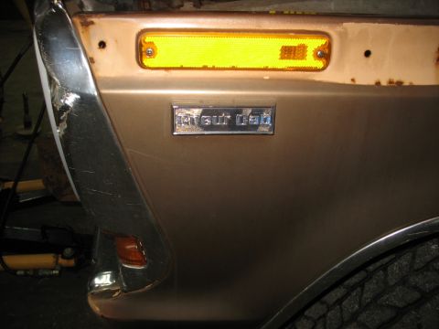 1978 Ford F-250 - A chrome "Sport Cab" emblem is visible on the fender of a brown truck, with a yellow marker light above it.