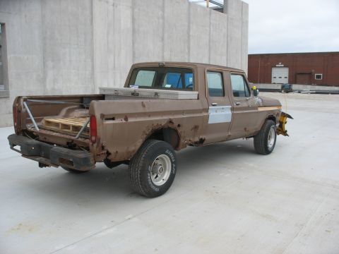 1978 Ford F-250 - This heavily rusted pickup truck has a snow plow attached and a toolbox in its bed.