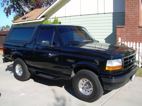 1986 Ford Bronco - This black Ford Bronco features tinted windows and a distinctive body style, likely from the mid-1990s.