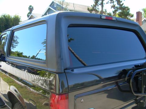 1986 Ford Bronco - Rear view of a black Ford Bronco, highlighting its tinted windows and body lines.