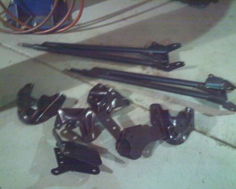 1992 Ford Bronco - Various black metal suspension components are laid out on a concrete surface.