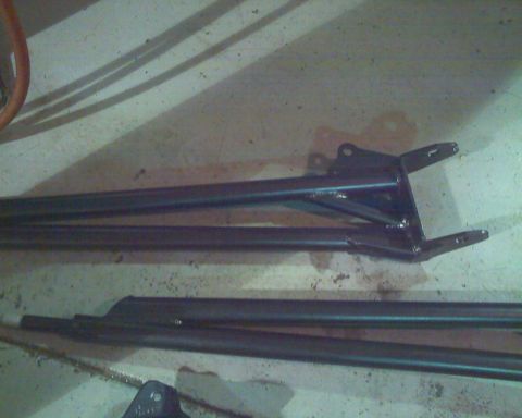 1992 Ford Bronco - Unidentified black suspension parts are laid out on a concrete surface, possibly for installation.