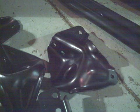 1992 Ford Bronco - Black metal brackets are laid out on a concrete surface, likely for installation.