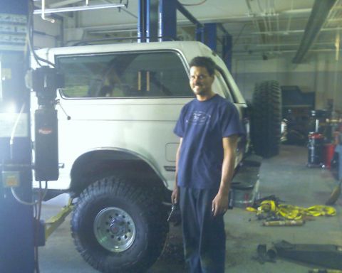 1992 Ford Bronco - A man stands next to a white 1992 Ford Bronco parked inside a garage.