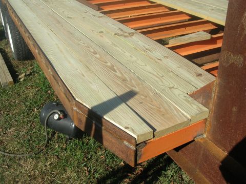1991 Ford F-150 - A gooseneck trailer's wooden deck and orange metal frame are visible, along with a tire and an air tank.
