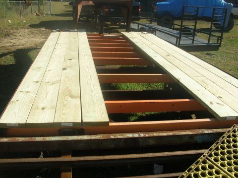 1991 Ford F-150 - A gooseneck trailer is being loaded with lumber, with a truck and another trailer visible in the background.
