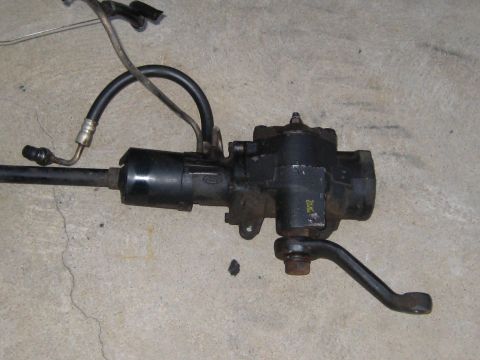 1996 Ford Bronco - Ford power steering gearbox with hoses attached, photographed on a concrete surface.