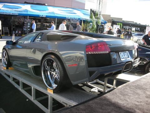 1998 Ford Crown Victoria - A gray Lamborghini Murciélago is displayed on a platform with custom wheels and a DUB license plate frame.
