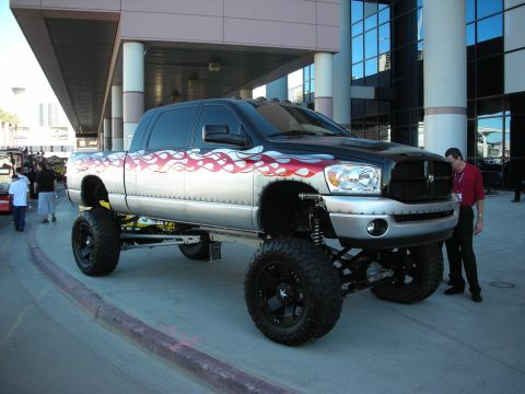 1998 Ford Crown Victoria - A heavily modified pickup truck is displayed outdoors with a man inspecting its front end.