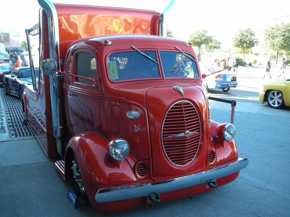 Red custom truck with chrome exhaust stacks and flame decals, viewed from the front